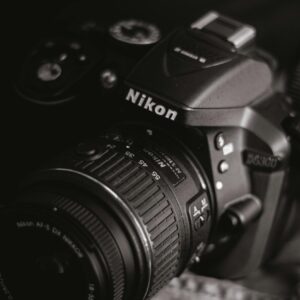 Artistic close-up of a DSLR camera in a black and white setting, emphasizing details and texture.
